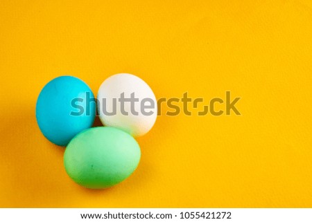 white, blue and green eggs on a yellow background, free place                              
