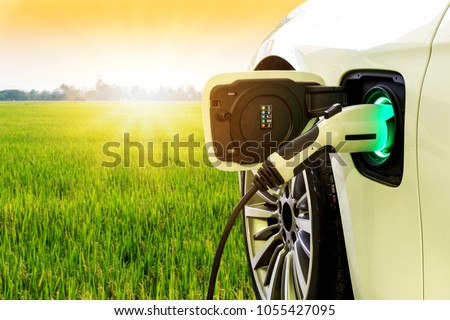 EV Car or Electric car at charging station with the power cable supply plugged in on blurred nature with soft light background. Eco-friendly alternative energy concept Royalty-Free Stock Photo #1055427095