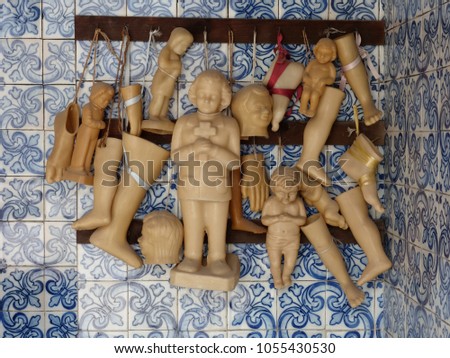 
Wax votives (head, foot, leg, hand, child, baby) in catholic church on a background of Portuguese tiles.