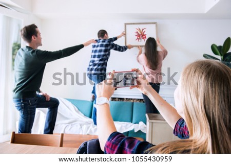 Young group of friends decorating the apartment and a woman taking a photo