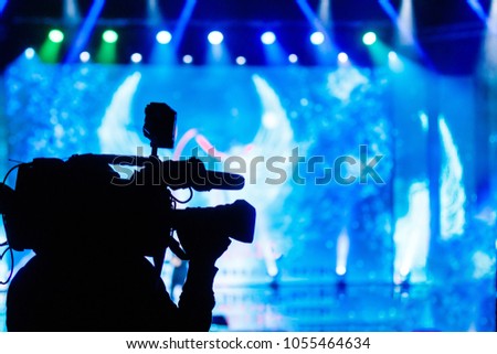 Professional Video camera operator working with his equipment, blue background