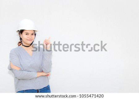 woman engineer wears Safety Helmet holding technical drawing and Thinking. with old white wall background.