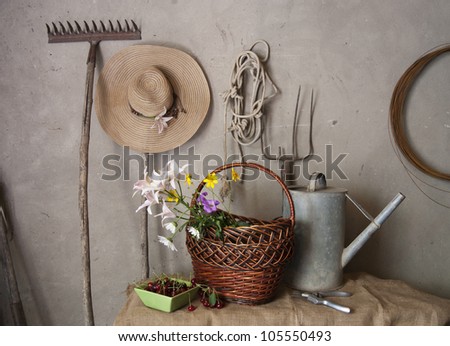  Still life of old garden tools, baskets of flowers and cherries