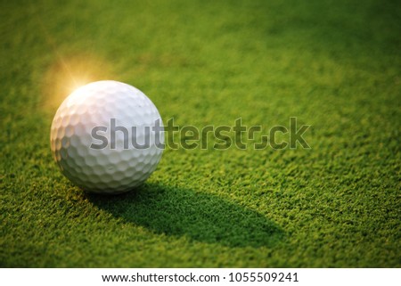 Golf ball on the green grass in beautiful golf course at sunset background. Golf ball on green in golf course at Thailand