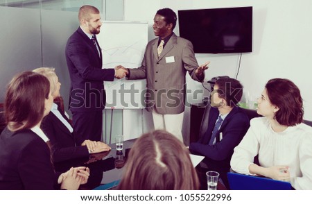 Strong handshake of two businessmen as sign of closing deal on meeting in boardroom 
