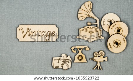 Vintage flat wooden things folded on a grey table. Telephone, phonograph, movie cameras, vinyl records and camera.
