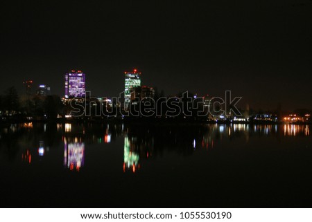 The city at night, a view from the park where the lights of the blocks are reflected in the water.
