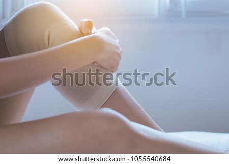 Woman using elastic bandage with leg,Female putting bandage on his injured knee,Selective focus
