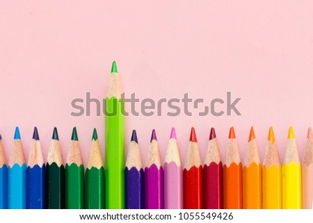 Color crayons in order one taller above on pink background