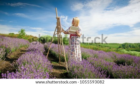 Beautiful woman in long dress painting picture of lavender field at Provence