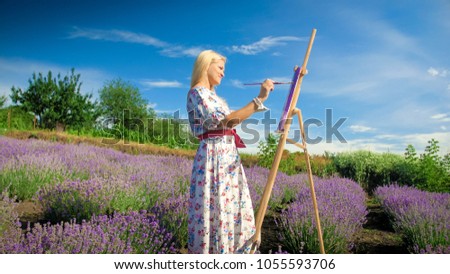 Smiling woman with easel drawing picture of lavender field
