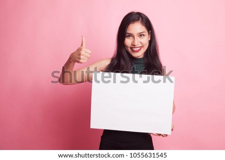 Young Asian woman show thumbs up with  white blank sign on pink background