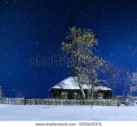 A starry sky over an abandoned house on the edge of the village on a winter night.