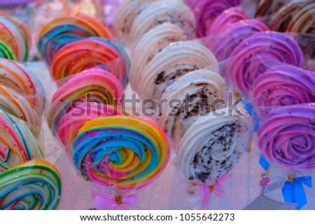 colorful candy sticks or lollipops wrapped with plastic bags and arranged in rows 