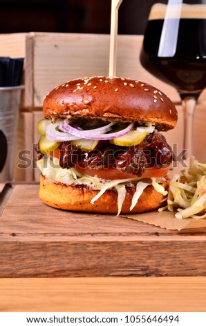 Fresh homemade hamburger with beef, onion, sause and cabbage garnish on a wooden board, wooden table background. Juicey gourmet burger, fast food concept.