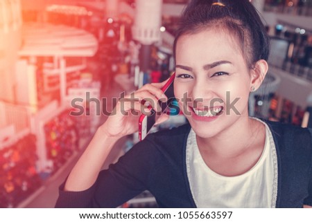 Picture of Asian woman talking on the phone while shopping at a shopping mall.Focus on face