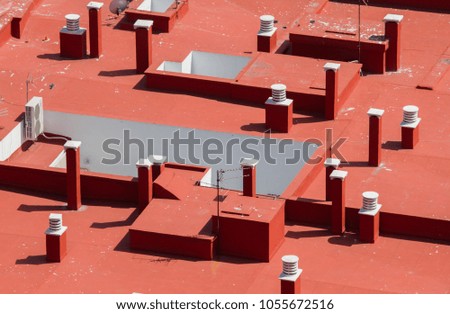 Modern red and white chimneys on red building roof