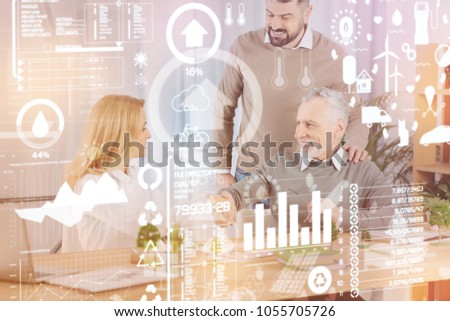 Shaking hands. Young beautiful woman smiling and shaking hands with a professional engineer with his positive colleague standing near and looking at them