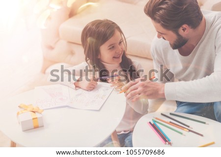 You are awesome. Sweet curious clever daughter and dad chatting in a living room while working on greeting car for celebrating mothers day