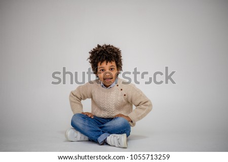 Lovely dark-skinned boy with age 6 years in different clothes shows different emotions on different backgrounds