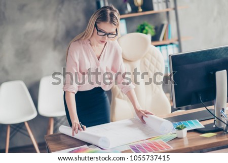 Pretty, attractive, charming, successful, stylish animator  open drawing sheet, whatman roll on the table, correcting plan, scheme, standing near desktop in workplace, workstation