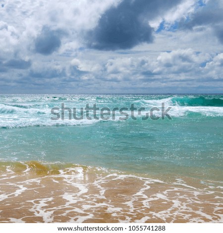 The sandy beach of the tropical ocean and the overcast sky with dramatic clouds.