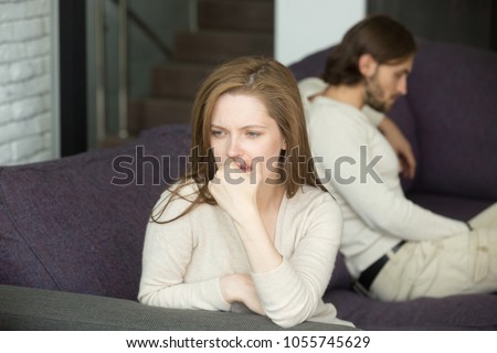 Sad disappointed wife not talking ignoring husband after fight sitting on sofa, upset frustrated woman feeling offended tired of problems, thinking of divorce or can not forgive betrayal cheating Royalty-Free Stock Photo #1055745629