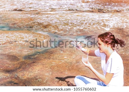 Thirsty redhead curle woman on dead desert pour from plastic bottle into a glass. Symbol of the drought and water shortage in technical disasters and climate calamities. global warming idea, sign