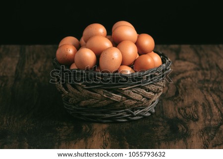 bunch of eggs in a basket on a wooden old retro table with black background