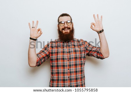 Cheerful bearded man with eyglasses showing OK gesture
