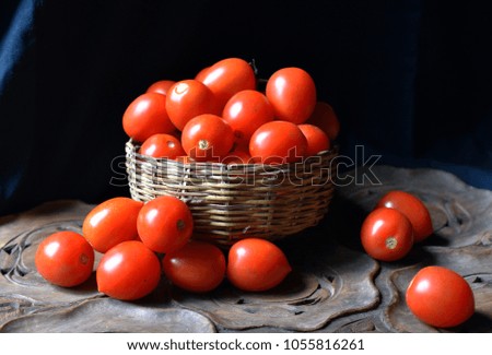 Still life photo small tomatoes in a basket on an old wooden tray