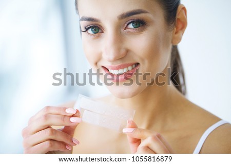 Teeth Whitening. Beautiful Smiling Woman Holding Whitening Strip. High Resolution Image