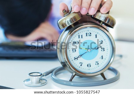 doctor man holding alarm clock on desk, man worried