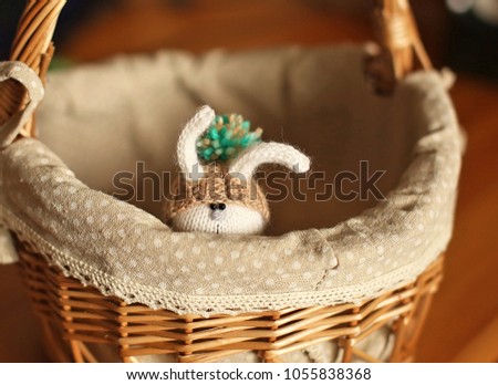 Easter Bunny in a hat with large pompom hiding and peeking out from large basket