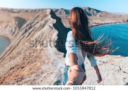 Girl walking on the mountain top over blue sea view. Follow me - POV. Royalty-Free Stock Photo #1055847812
