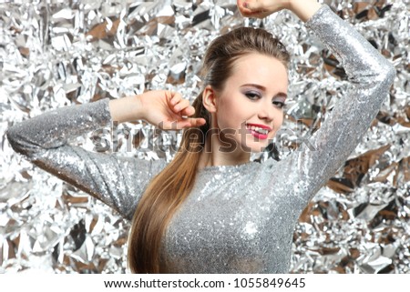Beautiful girl in a silver dress on a silver background. Futuristic style, glitter.