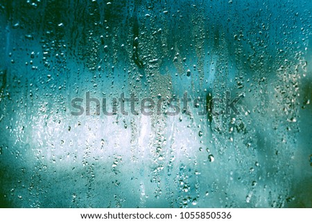 Window glass with condensation, strong, high humidity in room, large water droplet, cold tone