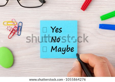 Hand writing Yes No Maybe on note with marker pen and glasses on wooden desk. Business concept.Top view. Royalty-Free Stock Photo #1055864276