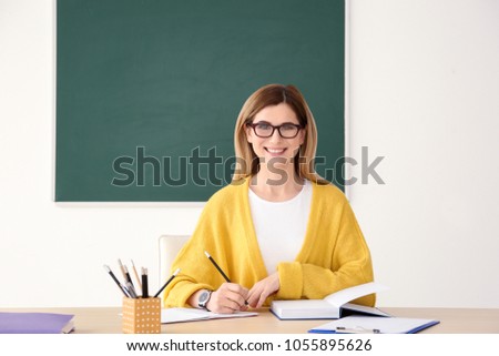 Young female teacher working at table in classroom