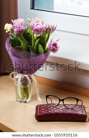 flowers in a vase, notepad glasses on a table
