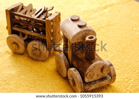 Wooden alphabet letters with toy bulldozer. Educational concept on yellow background