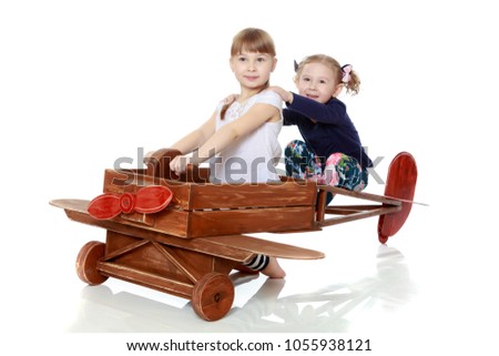 Two girls sister play with a wooden plane. The concept of a happy childhood, playing in the family. Isolated on white background.