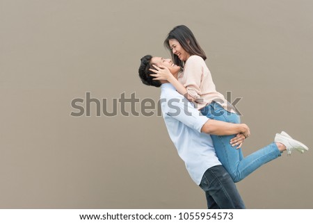 Attractive happy Asian couple in love having fun and hugging. Man lifting woman Royalty-Free Stock Photo #1055954573