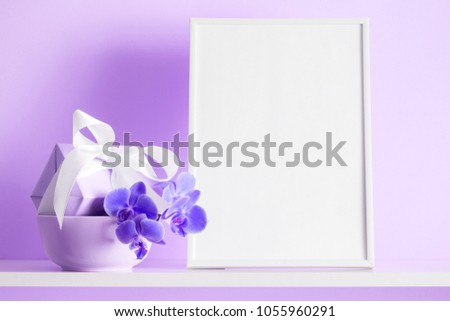 Photo frame mock up, beautiful flowers bouquet on the shelf, gift with white satin bow, lilac orchid on violet wall background.
