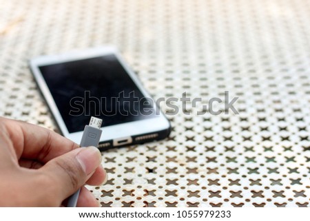 Micro usb in hand and smartphone background, Technology background, Charger background.