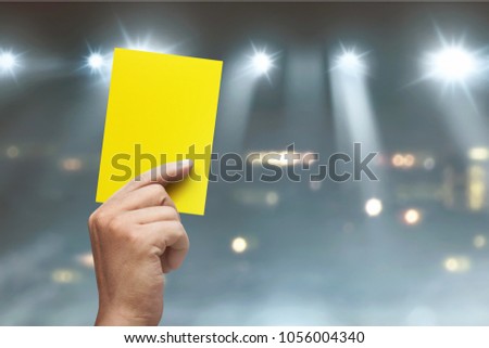 Hand of referee with yellow card on soccer stadium at match Royalty-Free Stock Photo #1056004340