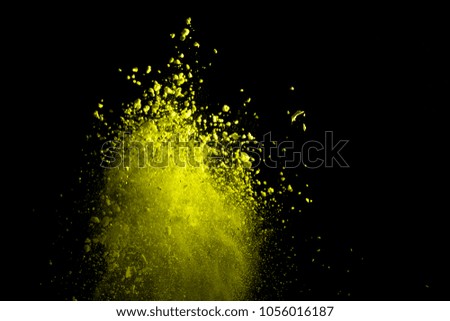 the explosion of yellow color powder on black background. Gold Color of dust or cloud explosive.