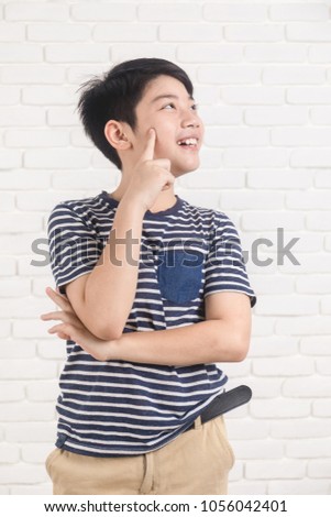 Portrait of asian cute boy thinking and smile on white brick wall background.