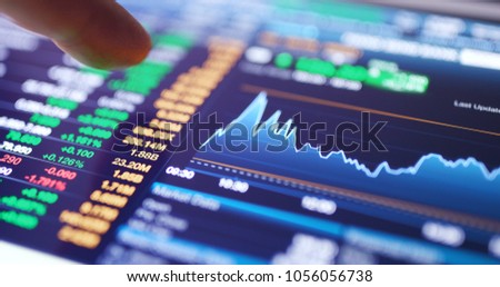 Working on digital tablet with stock market graph  Royalty-Free Stock Photo #1056056738