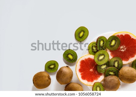 Cut Fresh Fruits, Grapefruit and Kiwi on a white plate and against a white background.